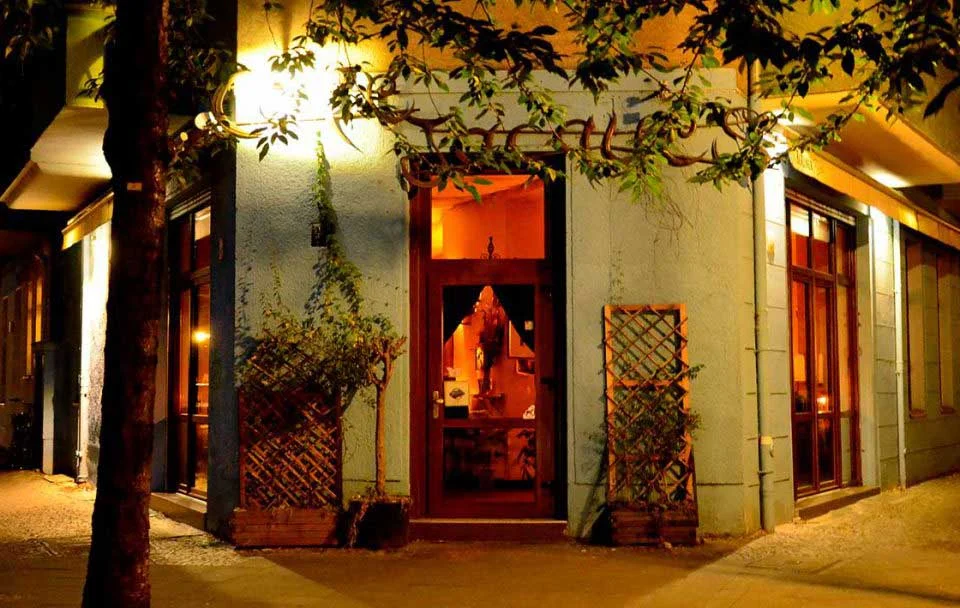 Beleuchteter Eingang des Café Jacques am Maybachufer bei Nacht
